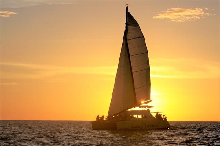 A catamaran under sail at golden hour off Playa Flamingo