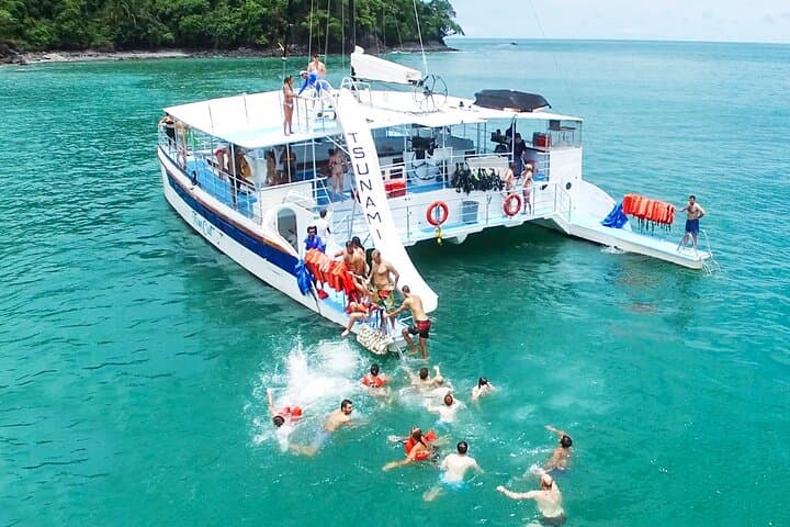 A catamaran anchored in turquoise water with swimmers alongside
